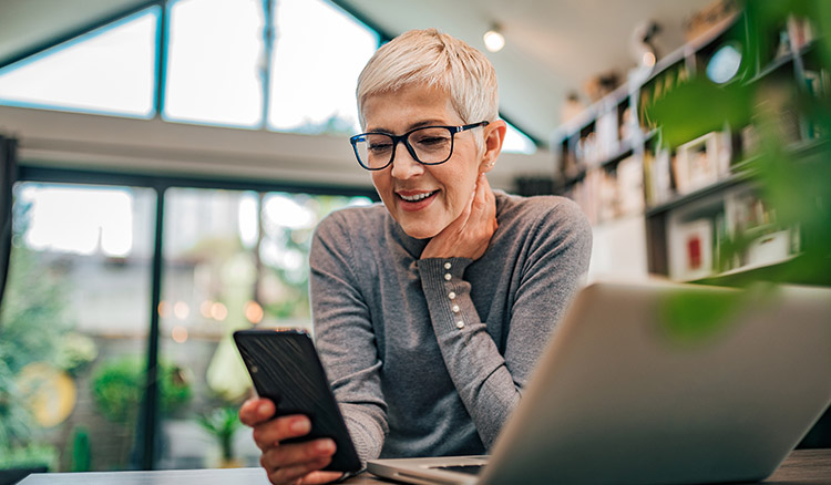 Mature Caucasian Female Using Phone And Laptop